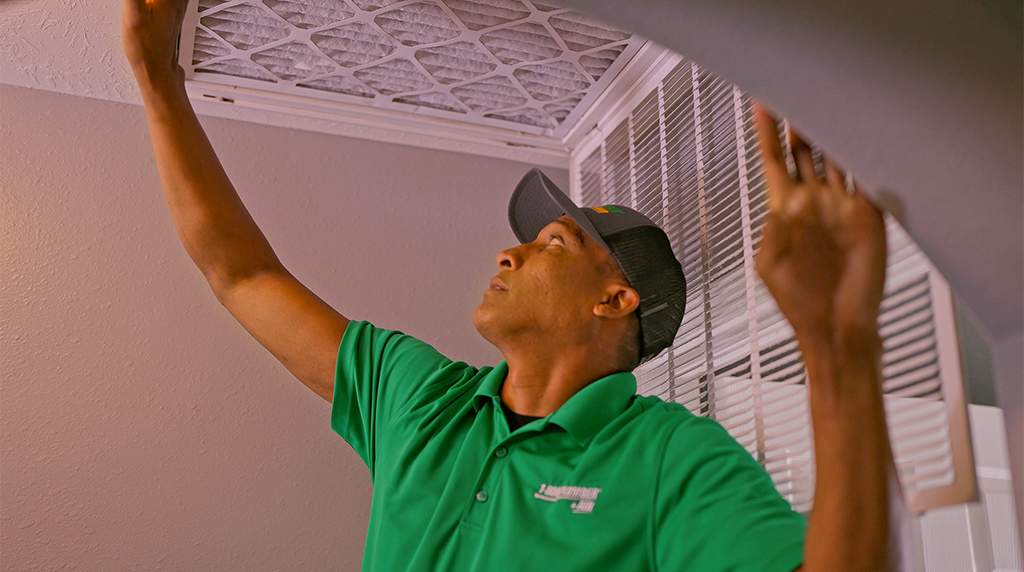 Your Heating Professionals - man replacing vent filter
